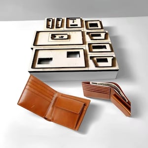 以下が含まれることがあります： 複数のカードスロットと小銭入れが付いた、2つの開いた茶色の革製財布。さまざまな長方形と正方形の切り抜きがある木製のレーザーカットオーガナイザーが背景にあります。