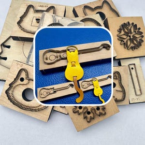 May include: Various wooden die-cut shapes, such as animal faces, snowflakes, and guitar outlines. A yellow leather cat-shaped keyring and a guitar-shaped keyring are visible. These items are likely for crafting or leatherworking projects.