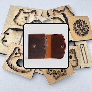 以下が含まれることがあります： スナップ留めとジッパー付きコンパートメントが付いた茶色の革製財布が表示されています。財布の周りには、動物の顔や雪の結晶のデザインなど、さまざまな木製の型抜き形状があり、工芸品に使用されています。