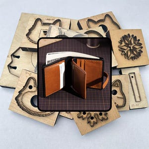 Puede incluir: Una cartera de cuero marrón con ribetes negros, abierta para mostrar dinero en efectivo y tarjetas. La cartera está rodeada de varias formas troqueladas de madera, incluyendo un copo de nieve y perfiles de animales. El fondo es un patrón de cuadrícula.
