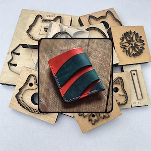 May include: A handcrafted red and green leather wallet with a bi-fold design. The wallet has two dark green stripes across the front. Various wooden craft tools surround the wallet, including die-cut shapes of animals and snowflakes.