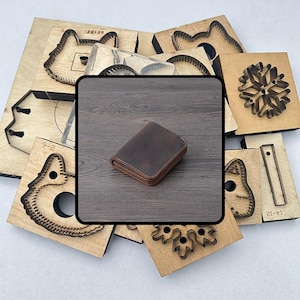May include: A brown leather wallet with a stitched border rests on a wooden surface, surrounded by wooden die-cut shapes. The wallet has a simple design. The die-cut shapes are for crafting.