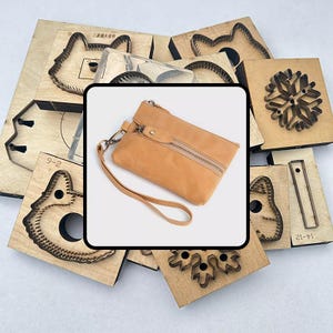 Könnte beinhalten: Eine hellbraune Leder-Handgelenktasche mit Reißverschluss und Handschlaufe. Die Handgelenktasche ist von verschiedenen Holzstanzformen umgeben, darunter Tiergesichter und Schneeflocken-Designs. Die Stanzformen sind aus Holz und Metall.