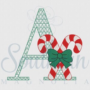 May include: A green embroidered letter A with two red and white candy canes crossed behind it and a green bow on top.