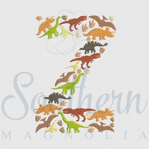 May include: A green, brown, orange, and yellow dinosaur design in the shape of the number 2. The dinosaurs are arranged in a way that creates the number 2.