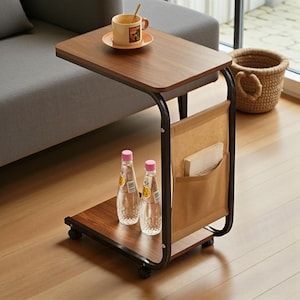 May include: A brown and black side table with a dark wood grain top and a lower shelf. The table has a black metal frame, a tan fabric pocket, and two clear water bottles. A cup of coffee sits on the table.