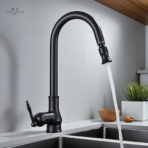 May include: A matte black kitchen faucet with a high-arc spout, water flowing into a stainless steel sink. The faucet features a pull-down sprayer and a single-handle lever. The VINTROA logo is visible in the upper left corner.
