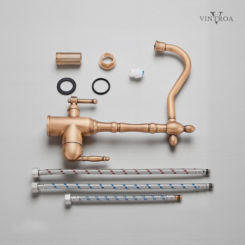 Puede incluir: Un grifo de cocina de bronce de estilo antiguo, con varios componentes dispuestos alrededor. El grifo presenta un ca&ntilde;o curvo, una manija de palanca y detalles decorativos. Incluye l&iacute;neas de suministro flexibles y otras piezas.