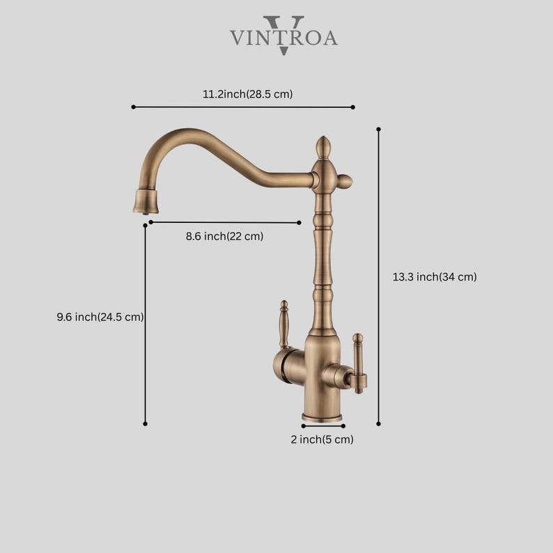 Puede incluir: Un grifo de cocina de color bronce con un ca&ntilde;o curvo y dos manijas. El grifo mide 28,5 cm de ancho, 22 cm de largo y 34 cm de alto. La base mide 5 cm de ancho. La marca "VINTROA" est&aacute; en la parte superior.