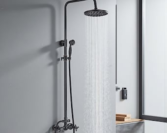 Op de afbeelding: Zwarte douchekraan met een ronde douchekop en een handdouche. De kraan heeft een vintage design met kruisvormige handgrepen en een gebogen arm. Water stroomt uit de douchekop. De merknaam "VINTROA" is zichtbaar.