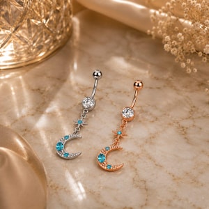 Puede incluir: Dos piercings para el ombligo, uno en tono plateado y otro en tono oro rosa. Cada uno presenta una bola superior con una piedra clara, un dije de estrella colgante y un dije de media luna con pequeñas piedras azul brillante en la curva.