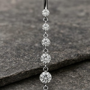 Könnte beinhalten: Ein Bauchnabelpiercing mit gebogenem Steg-Design. Der obere Ball ist schwarz, und der hängende Teil weist sieben runde, funkelnde, klare Edelsteine auf, die durch kleine silberne Ringe verbunden sind. Der Schmuck ist vor einem grauen Hintergrund platziert.