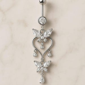 May include: A silver-colored belly button ring with a dangling design. The ring features a top ball, a large round gem, two butterfly-shaped designs with gems, and a heart-shaped design. The bottom of the ring has a teardrop-shaped gem.