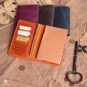 May include: An open orange leather journal with a gold pen, credit card slots, and a Visa card. The journal has a notepad inside and the text "Wishing you a season that's merry and bright! May this Christmas bring you endless joy and blessings."