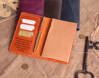 May include: An open orange leather journal with a gold pen, credit card slots, and a Visa card. The journal has a notepad inside and the text "Wishing you a season that's merry and bright! May this Christmas bring you endless joy and blessings."