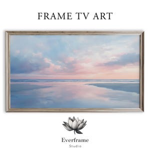May include: A framed landscape painting with a serene beach scene. The artwork features a pastel color palette of blues, pinks, and whites, depicting a tranquil sky and water reflection. The frame is a light, neutral color. Text at the top reads "FRAME TV ART".