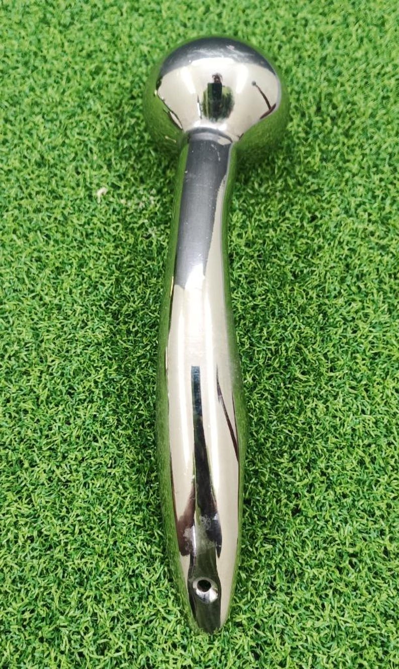 May include: A polished chrome shower head with a rounded top and a long, curved handle. The shower head is made of shiny metal and reflects the surrounding environment. The handle has a smooth, ergonomic design.