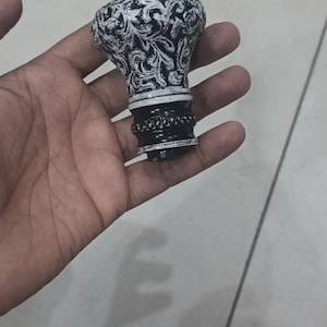 Peut inclure: Un bouchon de bouteille décoratif avec un motif floral noir et blanc. Le bouchon a un dessus arrondi et une base détaillée. Le design est complexe et détaillé, ajoutant une touche d'élégance.