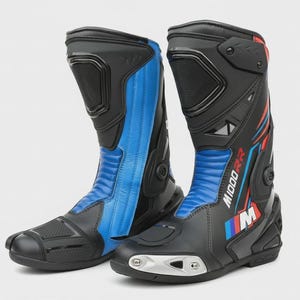 Könnte beinhalten: Paar schwarze und blaue Motorradstiefel mit dem Text "M1000RR" und dem BMW-Logo. Die Stiefel haben ein schlankes Design mit verstärkten Bereichen und einer Kombination aus schwarzen, blauen und roten Akzenten. Entwickelt für Schutz und Leistung.