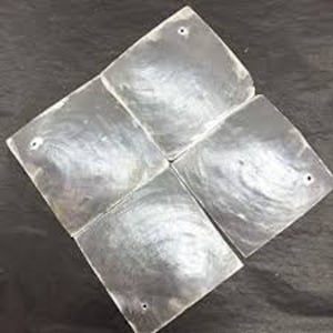 May include: Four iridescent white mother-of-pearl tiles with a hole in each corner. The tiles are arranged in a square pattern.