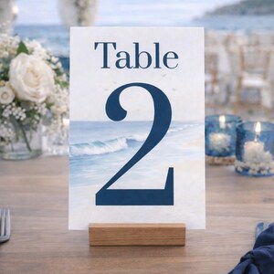 Ocean wedding signs bundle featuring a coordinated set of 13 printable ceremony and reception signs, including welcome sign, seating chart, timeline, bar signs, guest book, cards and gifts, favors, reserved, unplugged ceremony, and table numbers. Soft blue ocean background with elegant coastal typography creates a romantic beach and destination wedding look. Fully editable in Canva and available in multiple sizes, perfect for seaside, coastal, and tropical weddings.