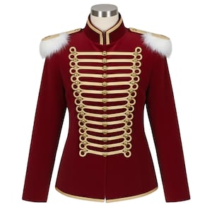 Puede incluir: Chaqueta burdeos de estilo militar con ribetes y botones dorados. La chaqueta presenta detalles de hombros de piel sintética blanca y un cuello alto. El diseño incluye una serie de lazos y botones decorativos en la parte delantera.