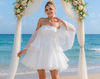 Ethereal short beach corset wedding dress with wing sleeves. Charming white bridal gown with a fluffy skirt