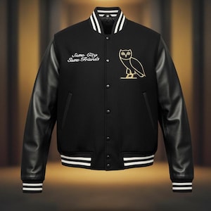 Puede incluir: Chaqueta universitaria negra con mangas de cuero negro, puños y cuello a rayas blancas. La chaqueta presenta el texto "Same City Same Friends" y un emblema de búho dorado en el pecho. Una prenda de abrigo clásica y elegante.