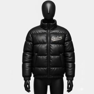 May include: Black puffer jacket with a high collar and a front zip. The jacket features the word "Custom" embroidered in white script on the chest. The jacket is displayed on a black mannequin.
