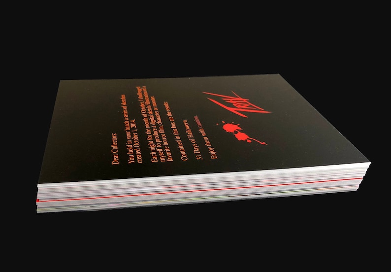 May include: A black book with red text and a red blood splatter design. The book is titled "31 Days of Halloween" and has the text "Enjoy them with" on the bottom. The book is stacked on top of other books.