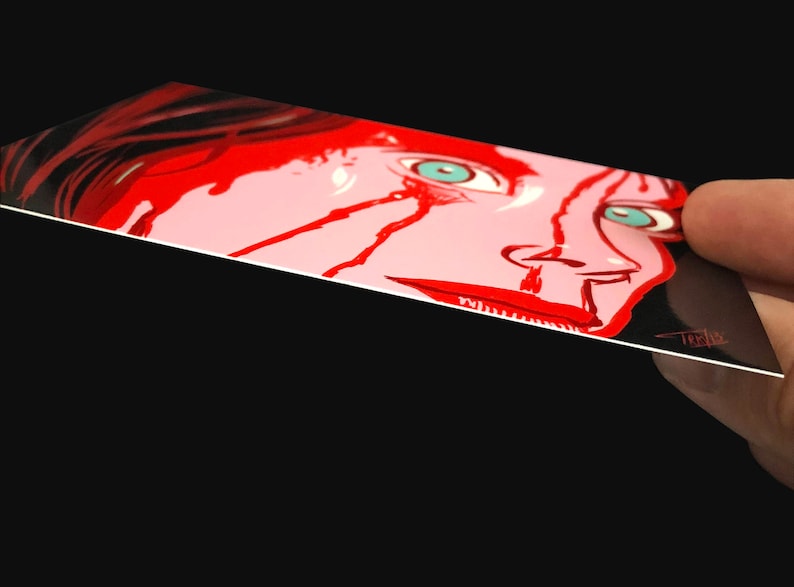 May include: A close-up of a woman's face with red paint splattered across her face and neck. Her eyes are wide open and her mouth is slightly open. The background is black.