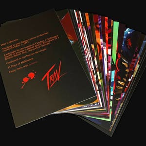 May include: A black and red card with the text "Dear Collectors" and "31 Days of Halloween" and the word "TRAV" in red. The card is part of a stack of cards with colorful illustrations.