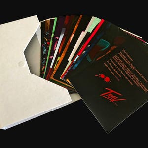 May include: A white envelope with a black button closure, containing a stack of black cards with red and white text. The text on the top card reads: "Dear Collectors, You hold in your hands a series of sketches created October 2013. Each image for the month of October, I challenged myself to create one (character) in the tradition of a 31 Days of Halloween. Contained in this book are the results. Enjoy them with..." The text is followed by the word "TRIAL" in red.