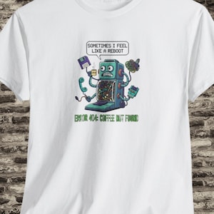 Puede incluir: Camiseta blanca con un robot de dibujos animados que sostiene un disquete y un teléfono. El robot tiene un bocadillo que dice "Sometimes I feel like a reboot". Debajo del robot, el texto dice "ERROR 404: COFFEE NOT FOUND."