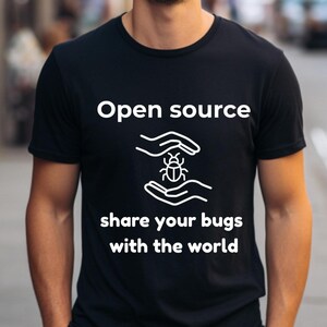 May include: Black t-shirt with white text and graphic. The text reads "Open source share your bugs with the world." The graphic depicts a bug between two hands. The shirt is a crew neck.