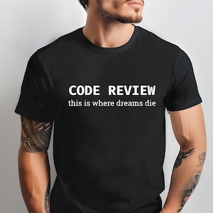 Op de afbeelding: Zwart t-shirt met de witte tekst "CODE REVIEW" en daaronder "this is where dreams die". Het t-shirt heeft een ronde hals en lijkt van zacht materiaal te zijn.
