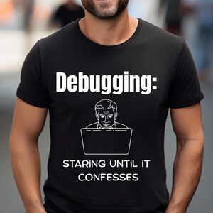Peut inclure: T-shirt noir avec l'inscription blanche "Debugging: Staring Until It Confesses". Le t-shirt présente un dessin d'une personne devant un ordinateur portable. Un design humoristique pour les programmeurs.