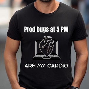 Op de afbeelding: Zwart T-shirt met witte tekst en afbeelding. De tekst luidt "Prod bugs at 5 PM ARE MY CARDIO." De afbeelding is een hart in een laptopscherm. Het shirt heeft korte mouwen.
