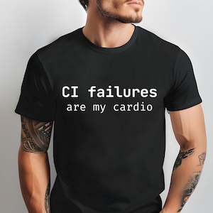 May include: Black t-shirt with the white text "CI failures are my cardio." The shirt has a crew neck and short sleeves. The text is centered on the front of the shirt.
