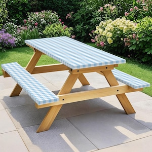 May include: A wooden picnic table with attached benches. The table and benches have a light blue and white checkered pattern. The table is set on a patio with a garden in the background.