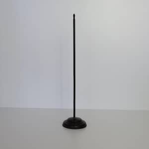 May include: A black metal table number holder with a round base and a tall, slender stem. The top of the stem has a small, pointed finial. The holder is designed to display table numbers or signs.