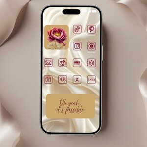 May include: A smartphone screen displays a custom app icon set with a floral design and various social media and app icons in a burgundy color. The screen also features the text "Oh yeah, it's possible" in a script font, set against a tan background.