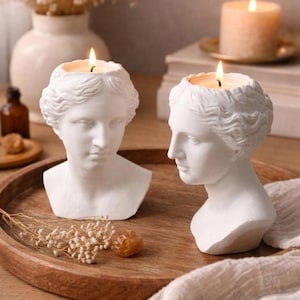 Può includere: Una tazza di ceramica bianca con manico nero e la scritta "But First, Coffee" in nero, in grassetto. La tazza è appoggiata su una superficie di legno. La tazza è alta circa 10 cm.