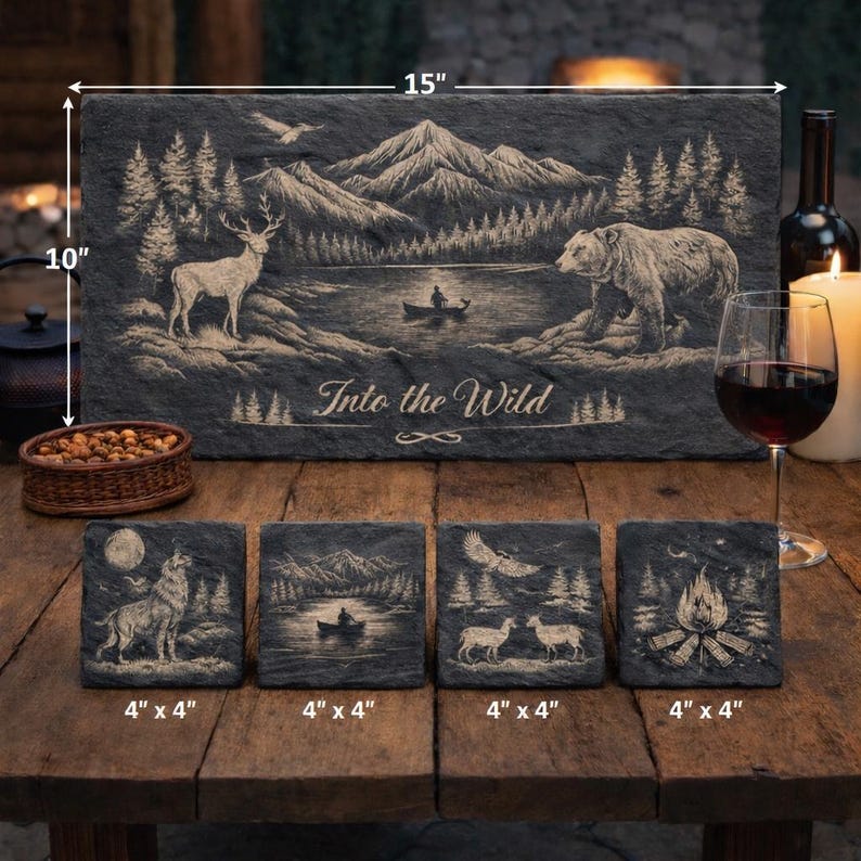 May include: A slate serving board, 15" x 10", and four 4" x 4" coasters with engraved nature scenes. The board features a mountain lake scene with a deer, bear, and text "Into the Wild". The coasters depict a wolf, boat, eagle, and campfire.