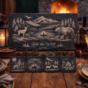 May include: A rustic slate serving board and coasters set with a nature-themed design. The large board features a mountain and lake scene with a deer, bear, and the text "Into the Wild." Four matching coasters depict wildlife and landscapes.