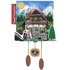 Può includere: Un orologio a cucù decorativo con un design a chalet svizzero, con una facciata dettagliata, un sole, montagne e una mucca. L'orologio ha un pendolo con un uccello e due pesi a forma di pigna. Il testo "Swartzwald" è sul lato.