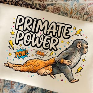 Peut inclure: Sac fourre-tout blanc cassé avec l'inscription "PRIMATE POWER" et une illustration de singe de dessin animé. Le singe est gris et orange, avec des éclairs et des étoiles jaunes. Les mots "POW!" et "BAM!" sont également inclus.