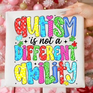 Peut inclure: Tissu carré blanc avec le texte "AUTISME n'est pas une CAPACITÉ DIFFÉRENTE" en lettres colorées et audacieuses. Le mot "AUTISME" est en rouge, jaune, vert et bleu. Le mot "DIFFÉRENT" est en rouge, jaune, rose et vert. Le mot "CAPACITÉ" est en jaune, bleu, rose et rouge.