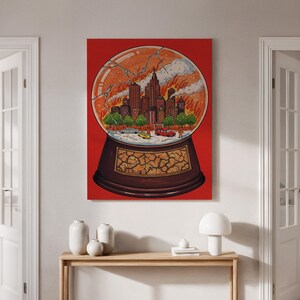 May include: Canvas print of a city on fire inside a snow globe, set against a red backdrop. The artwork shows a burning cityscape with smoke. The snow globe rests on a brown base. The glass has a cracked effect.