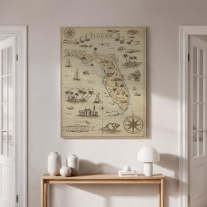 May include: A framed vintage map of Florida, with detailed illustrations of landmarks, sailboats, and palm trees. The map includes the word "Florida" in a banner at the top and bottom. The colour palette is neutral, with a sepia tone.